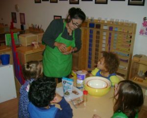 a teacher guiding students through a Montessori art project